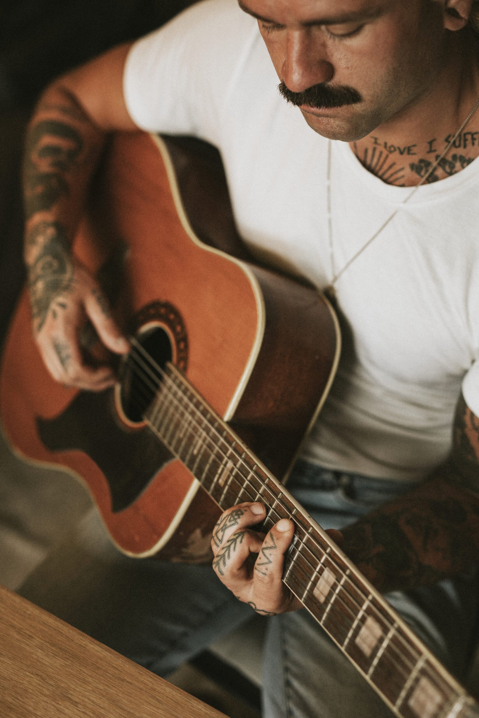 Tattooed singer songwriter playing an acoustic guitar